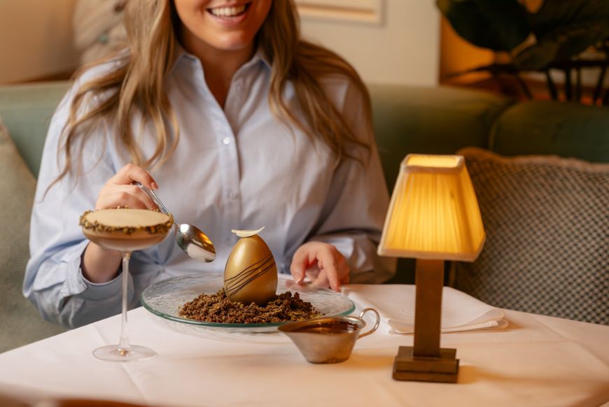 a woman sitting at a table eating an easter egg